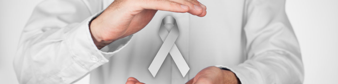 Close-up of man in off-white shirt with hands framing a floating grey Parkinson’s awareness ribbon on a white background.