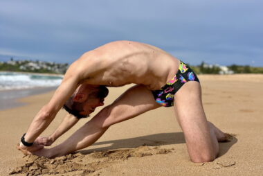 Coach Trent Renshaw performing a modified Cossack squat stretch after a soft sand run on Bombo Beach.