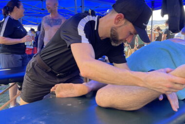 Massage therapist Trent Renshaw treating a runner’s adductors with a passive soft tissue release technique in a side-lying position at the Coffs Run Festival 2024.
