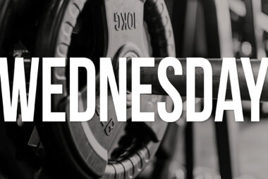 Monochrome close-up of weight plates on a barbell with the word “WEDNESDAY” in white text overlaid.