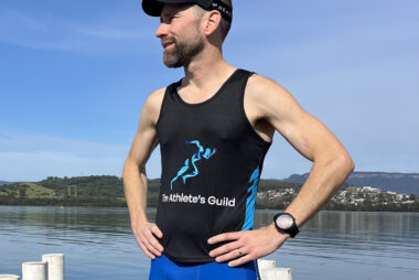Coach Trent Renshaw standing on a jetty at Lake Illawarra after completing a 10km base run.