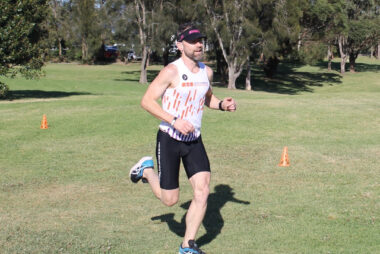 Coach Trent Renshaw wearing Coffs Tri Club singlet and black tights at Shellharbour Parkrun.