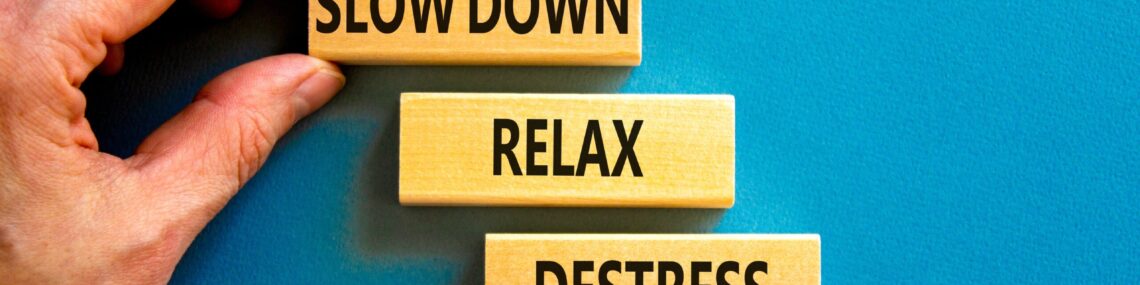 Man placing wooden pieces labelled “slow down,” “relax,” and “destress” onto a blue felt board.
