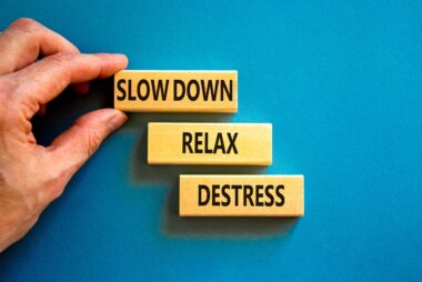 Man placing wooden pieces labelled “slow down,” “relax,” and “destress” onto a blue felt board.