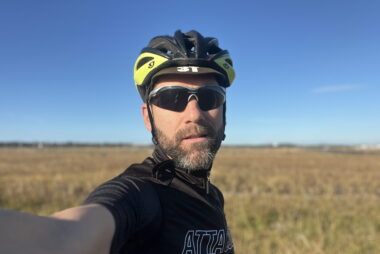 Coach Trent Renshaw cycling at Enterprise Park with Coffs Harbour Airport blurred in the background.