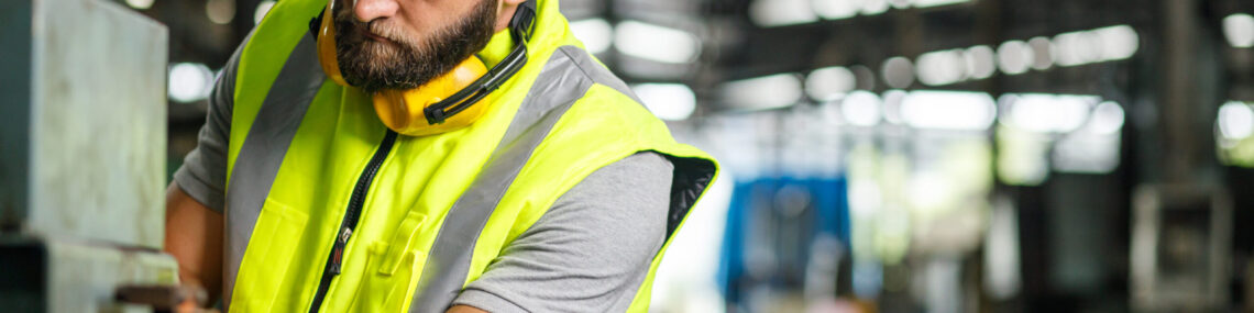 Mechanical engineer or tradesman setting up and checking industrial equipment.