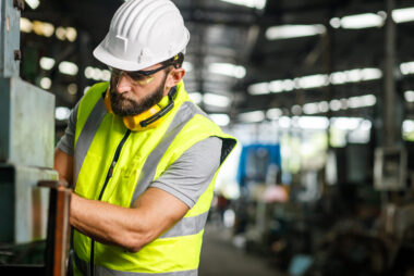 Mechanical engineer or tradesman setting up and checking industrial equipment.