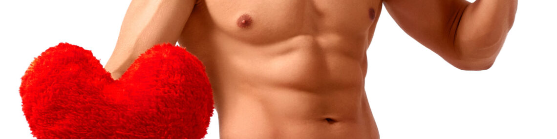 Shirtless man in red board shorts holding a plush heart-shaped cushion in one hand and a large red gift box with a white bow against his chest.