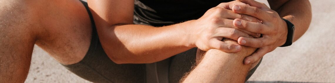 Sportsman holding his knee in discomfort after exercise, symbolising joint pain and the impact of arthritis on athletes.
